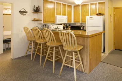 a kitchen with wooden cabinets and a island with bar stools at St Anton Condos with Rec Center in Mammoth Lakes