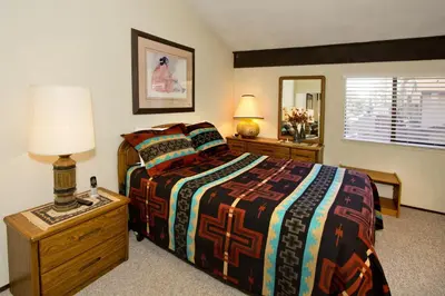 a bedroom with a bed and a table with a lamp at St Anton Courtyard View 2-Bedroom Condo with full kitchen in Mammoth Lakes