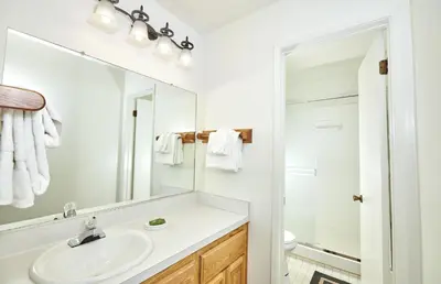 a white bathroom with a sink and a mirror at St Anton Wooded View 2-Bedroom Condos with Ski Lockers in Mammoth Lakes