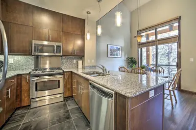 a kitchen with stainless steel appliances and wooden cabinets at Modern Mammoth Lakes Condo Ski, Hike, and More! in Mammoth Lakes