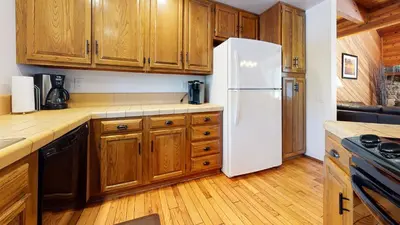 a kitchen with wooden cabinets and a white refrigerator at Snowflower #20 condo in Mammoth Lakes