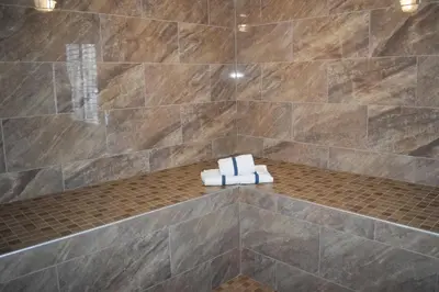 a bathroom with a tiled shower with two folded towels at Baymont by Wyndham Manteca in Manteca