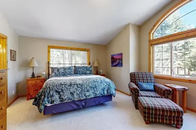 a bedroom with a bed and a chair at Sugar Pine Haus in Tahoma