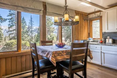 a dining room with a table and chairs and windows at Brand New Listing! 5 minute walk to Canyon Lodge! Newly Updated Two-Bed, Two-Bath, Mountainback #14 in Mammoth Lakes