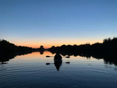 a person in a kayak on a river at sunset at Year-round fishing, boating, birding, 1 hr from SF in Walnut Grove