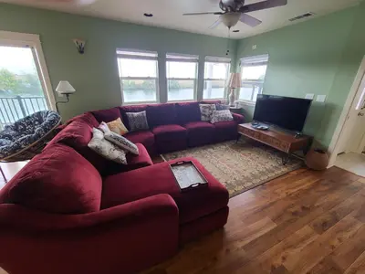 a living room with a red couch and a flat screen tv at Year-round fishing, boating, birding, 1 hr from SF in Walnut Grove