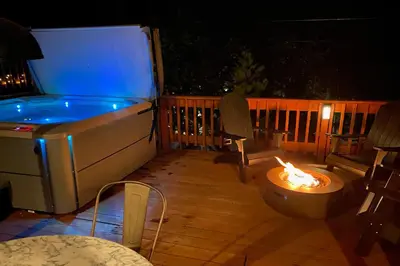 a hot tub and a fire pit on a deck at night at Heavenly Daze in Arnold
