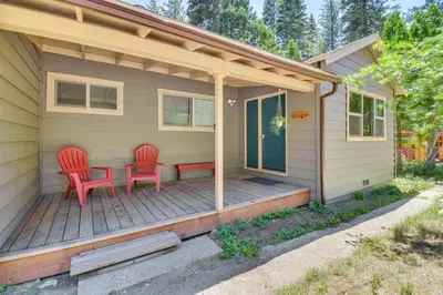 a house with two red chairs on a porch at Cozy Retreat with Deck about 2 Mi to Pinecrest Lake! in Strawberry