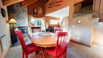 a dining room with a wooden table and red chairs at Mammoth View Villas #3 condo in Mammoth Lakes