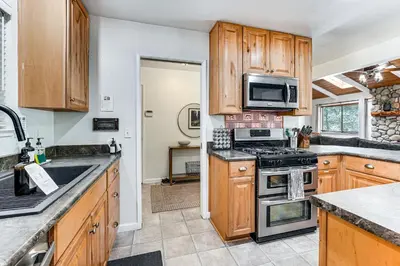 a kitchen with wooden cabinets and a stove top oven at Arnold Family Cabin with Hot Tub, Arcade and Deck in Arnold