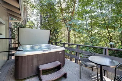 a hot tub on a deck with a table and chairs at Arnold Family Cabin with Hot Tub, Arcade and Deck in Arnold