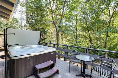 a hot tub on a deck with chairs and a table at Arnold Family Cabin with Hot Tub, Arcade and Deck in Arnold