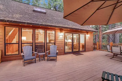 a wooden deck with chairs and a table and an umbrella at Worth The Waite in Arnold