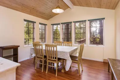 a dining room with a table and chairs and windows at Cedar Nest in Wawona