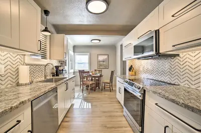 a kitchen with white cabinets and a dining room at Game Room and Putting Green Reno Home! in Reno