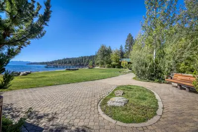 a brick walkway next to a park with a bench at Tahoe's Stunner in Tahoe Vista