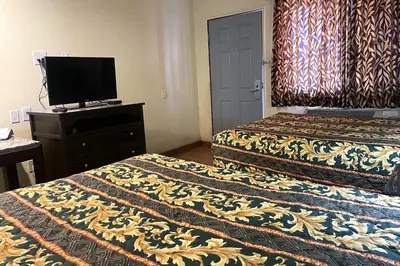 a hotel room with two beds and a flat screen tv at Sunstar Inn Los Banos near I-5 in Los Banos