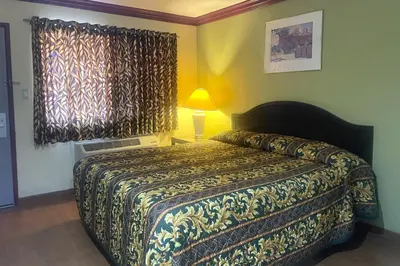 a bedroom with a bed and a lamp and a window at Sunstar Inn Los Banos near I-5 in Los Banos