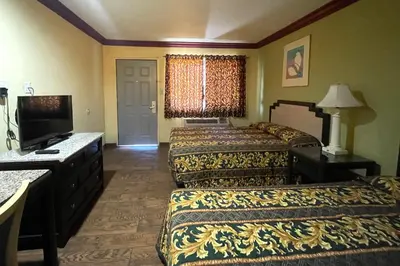 a hotel room with two beds and a flat screen tv at Sunstar Inn Los Banos near I-5 in Los Banos