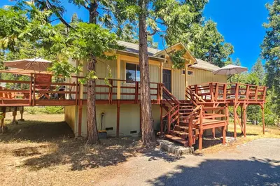 a house with a deck with chairs and umbrellas at Redwood Escape in Arnold