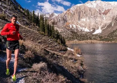 a man running on a hill next to a body of water at Two-Bedroom Apartment in Mammoth Lakes