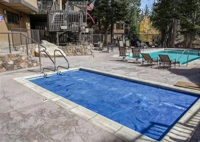 a large blue swimming pool with chairs next to a building at Two-Bedroom Apartment in Mammoth Lakes