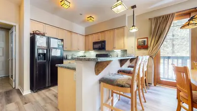 a kitchen with a black refrigerator and wooden cabinets at Mammoth Green #111 condo in Mammoth Lakes