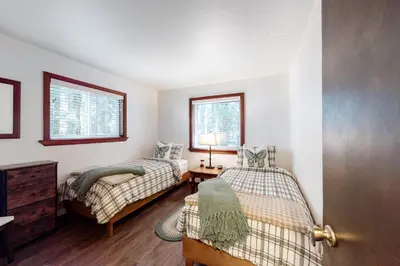 a bedroom with two beds and a dresser and two windows at Truckee Mountain Retreat in Truckee