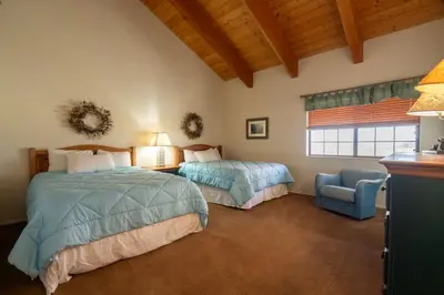 a bedroom with two beds and a chair and a window at Rr-interlaken 19 in June Lake