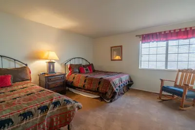 a bedroom with two beds and a chair and a window at Rr-interlaken 19 in June Lake