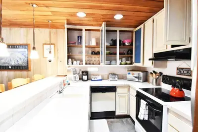a kitchen with white cabinets and black appliances at COZY Condo at Canyon Lodge! Sleeps 8, a walk to Canyon Lodge in Mammoth Lakes