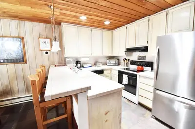 a kitchen with white cabinets and a stainless steel refrigerator at COZY Condo at Canyon Lodge! Sleeps 8, a walk to Canyon Lodge in Mammoth Lakes