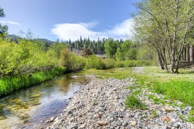 a river with rocks and trees in a field at Big Creek Inn in Fish Camp