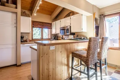 a kitchen with white cabinets and bar stools at Sunrise 9 in Mammoth Lakes
