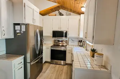 a kitchen with white cabinets and a stainless steel refrigerator at Cabin In The Woods in Arnold