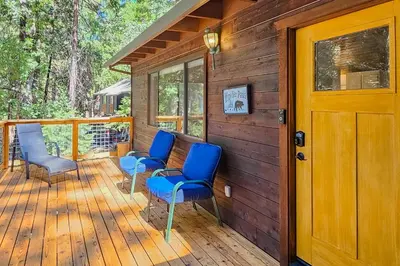 a wooden deck with blue chairs and a wooden door at Cabin In The Woods in Arnold