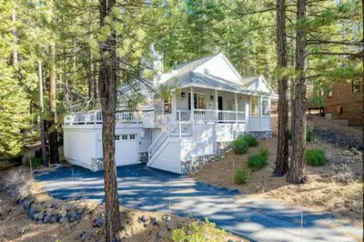a white house with a garage in the woods at Mountainside Retreat in Truckee