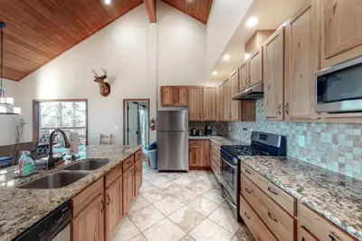 a kitchen with wooden cabinets and a stainless steel refrigerator at Glacier Peak Lodge in Yosemite West