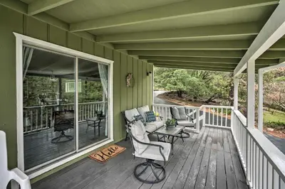 a green house with a porch with chairs and a fireplace at Forest-View Deck and Fire Pits Pine Grove Retreat! in Jackson