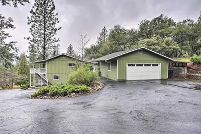 a green house with a white garage at Forest-View Deck and Fire Pits Pine Grove Retreat! in Jackson