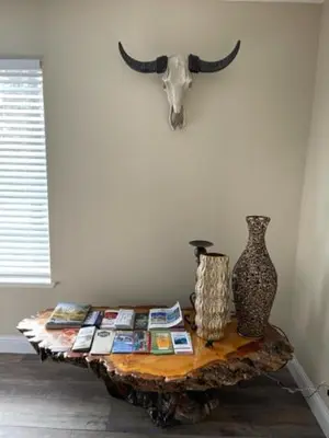 a table with a cow skull on the wall and a table with magazines at Beautiful 3 bedroom home located near Yosemite in Oakhurst