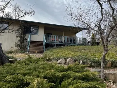 a house with a porch and stairs in a yard at Beautiful 3 bedroom home located near Yosemite in Oakhurst