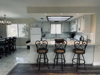 a kitchen with three bar stools and a kitchen with a counter at Beautiful 3 bedroom home located near Yosemite in Oakhurst