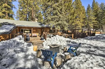 a log cabin in the snow with two chairs at Dog-Friendly Kings Beach Log Cabin with Hot Tub! in Kings Beach