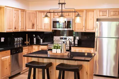 a kitchen with wooden cabinets and a stainless steel refrigerator at Sequoia Trails, mountains, fun & relax in Ponderosa