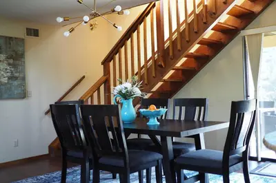 a dining room table with chairs and a blue vase on it at Yosemite Riverside Retreat with small beach access and air conditioning in Oakhurst