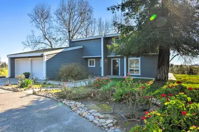 a house with a tree and flowers in front of it at Picturesque Farmhouse on Working Almond Ranch in Oakdale