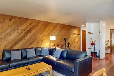 a living room with a leather couch and a wooden wall at Snowcreek 27 in Mammoth Lakes