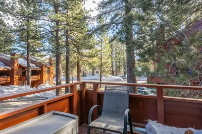 a chair on the deck of a cabin in the woods at Spacious Winterset 26 2 Bedrm Plus Loft 3 Full Bathrm Townhome Sleeps 8 Steps to Free Town Shuttle in Mammoth Lakes