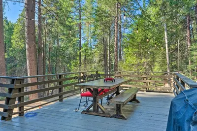 a picnic table on a wooden deck in the woods at Walk Downtown Arnold Cabin with Large Deck! in Arnold